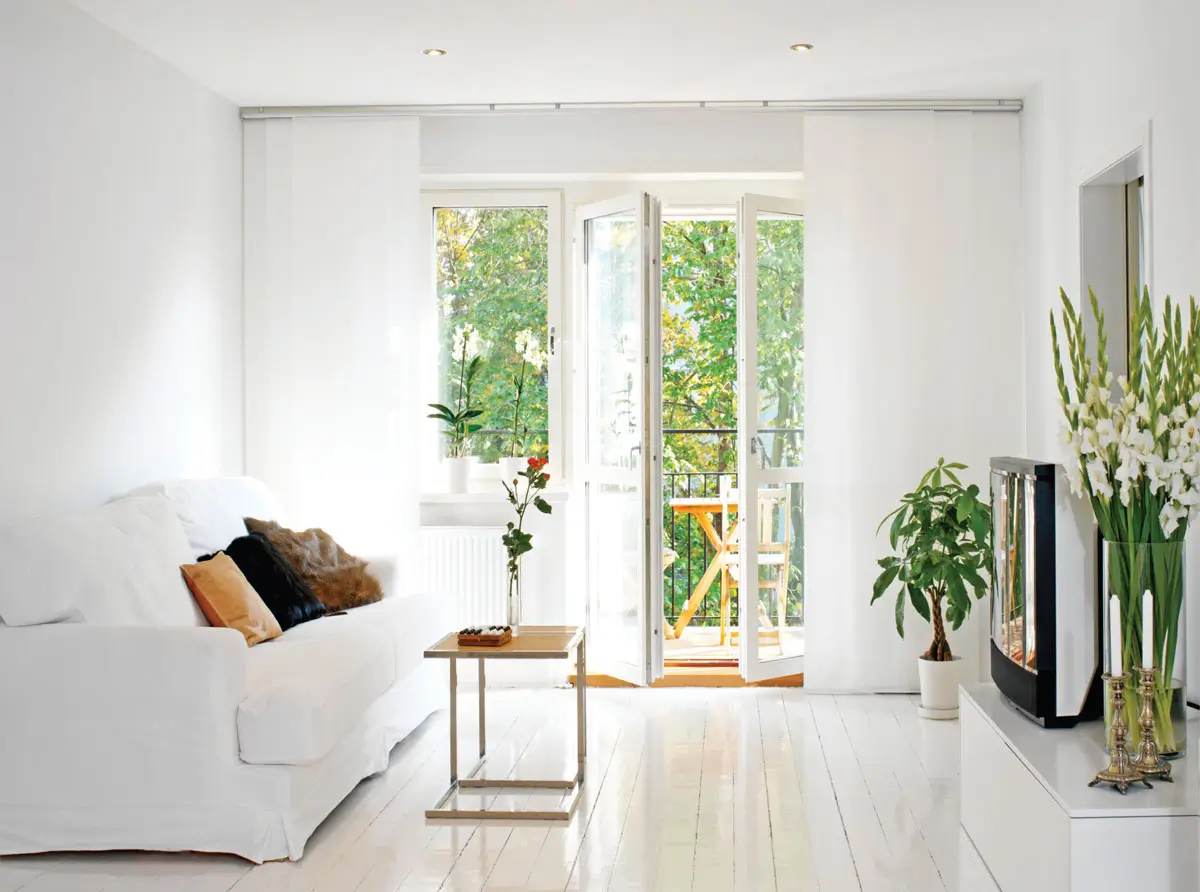 Sala minimalista con puerta francesa de PVC blanco y doble vidrio hermético que permite entrada de luz natural y mejora el aislamiento acústico y la eficiencia energética del hogar.