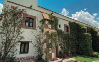 Fachada residencial con ventanas de PVC que ofrecen aislamiento térmico y acústico, diseño arquitectónico elegante y eficiencia energética en entorno natural.