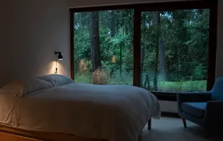 Recámara moderna con ventana de PVC de gran formato que ofrece aislamiento acústico y térmico, proporcionando confort, silencio y eficiencia energética en entorno natural.