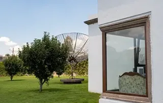 Ventana de PVC instalada en fachada residencial con vista al jardín, diseñada para ofrecer aislamiento térmico, eficiencia energética y alto rendimiento acústico en proyectos residenciales.